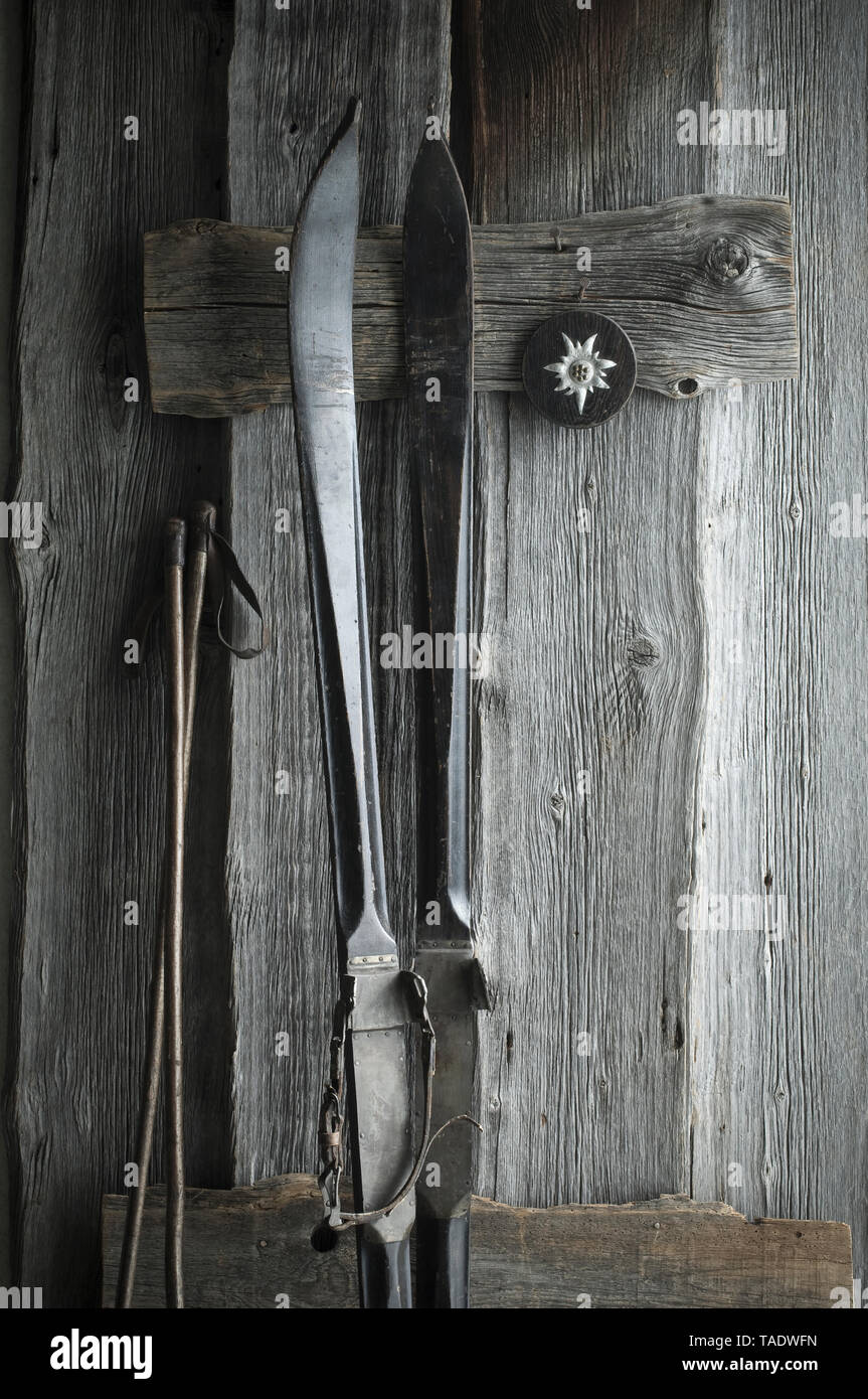 Alte Skier und Stöcke lehnte sich auf Holz- wand, Edelweiss Stockfoto