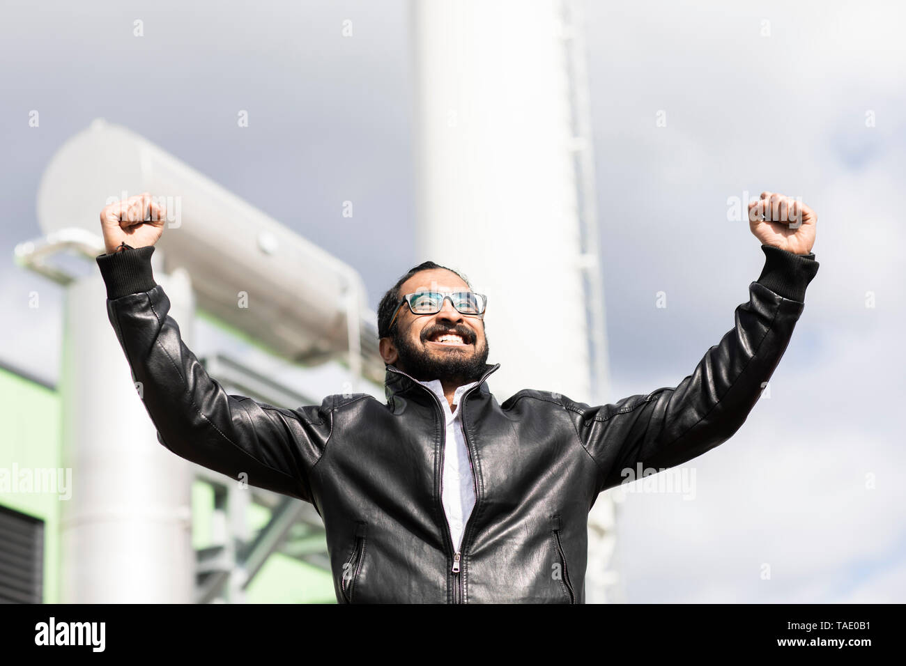 Portrait von glücklichen Mann mit Brille und schwarzen Lederjacke vor power station Stockfoto