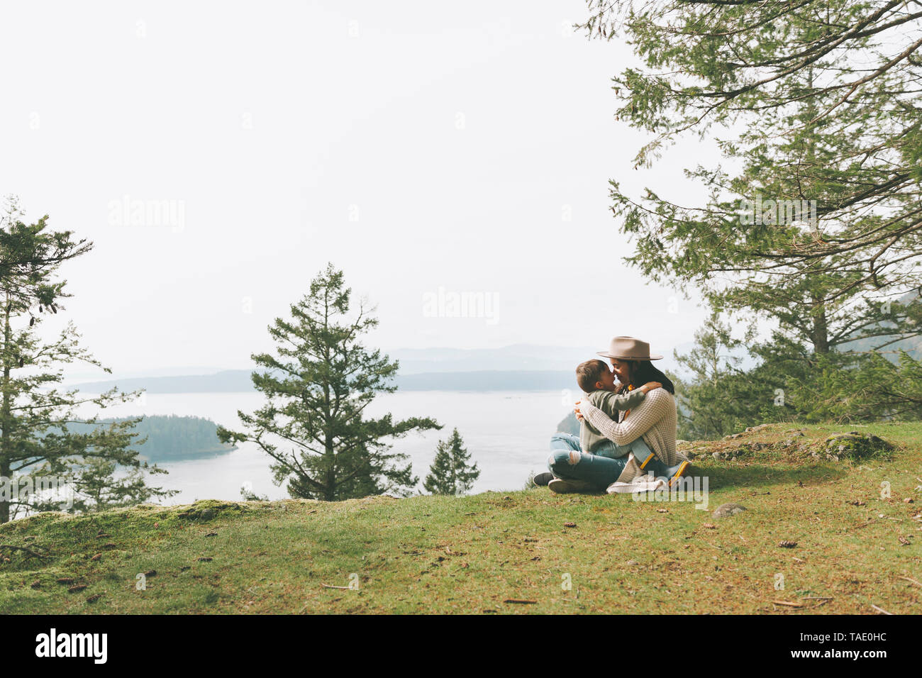 Mutter sitzt auf Gras, ihr Sohn kuscheln in der Natur Stockfoto