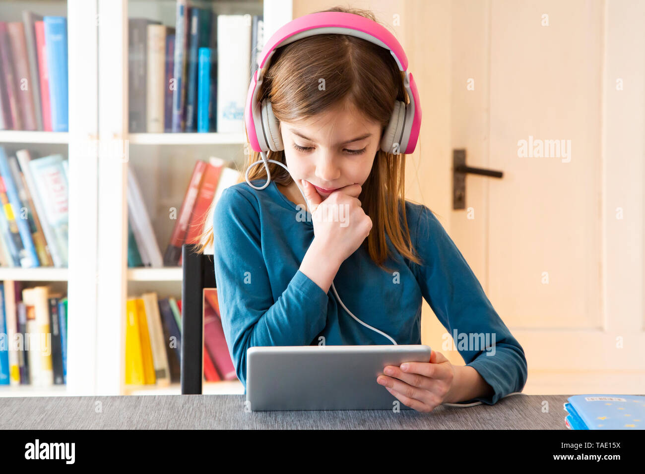 Kleines Mädchen mit Hausaufgaben mit Kopfhörern und digitale Tablet Stockfoto