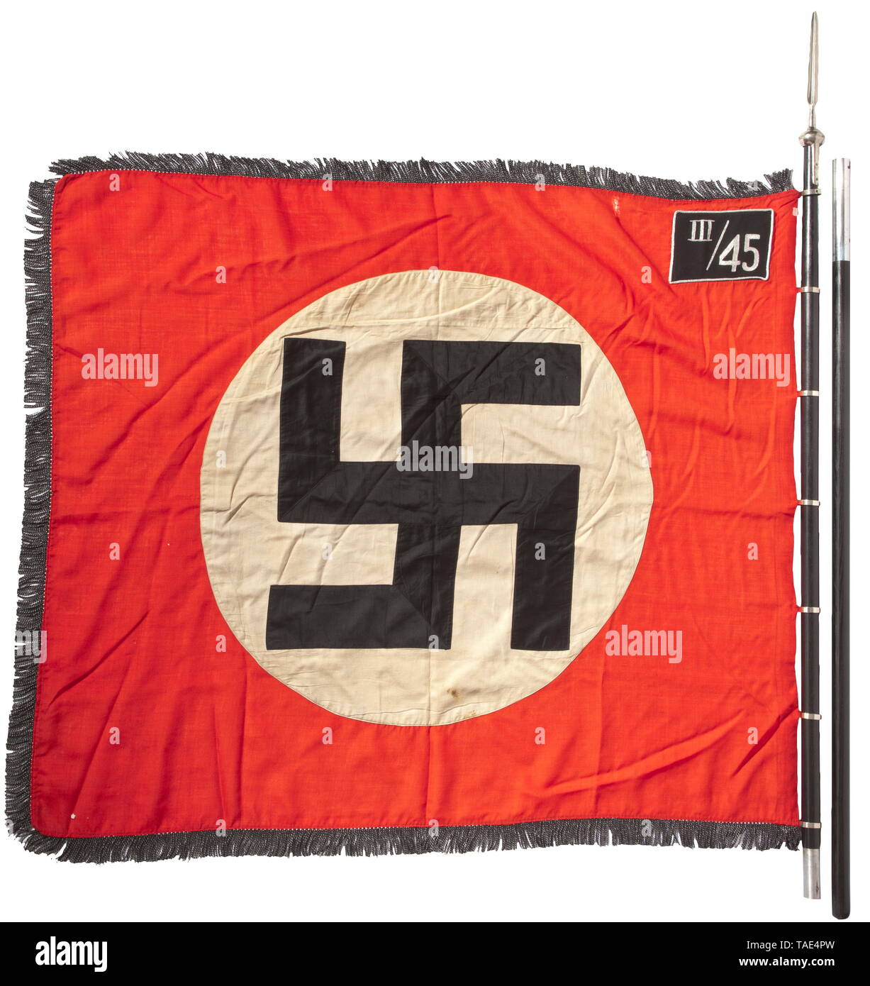 Ein SS-Sturm Flagge von III/45 in Rosenberg/Oberschlesien mit Pol und Finial Rote Fahne Stoff mit schwarz-silbernen Fransen auf drei Seiten, auf beiden Seiten mit einem GENÄHTEN - In weißen Scheibe und eine schräge Hakenkreuz mit schwarzen Flächen in silberne Schnur getrimmt. Silber bestickt" III/45' für die 3 Sturmbann (Rosenberg O. S) von 45 SS-Standarte (Neiße O.S.). Sieben direkt aufgenähten Vernickelt standard Ringe. Lieferung stanzen, kleinen Schönheitsfehlern. Abmessungen Ca. 120 x 145 cm. Zweiteilige schwarze hölzerne Flagstaff. Vernickelt finial in Form einer Lanze Tipp, Gelocht' RZM M 3/39/40, Editorial-Use - Nur Stockfoto
