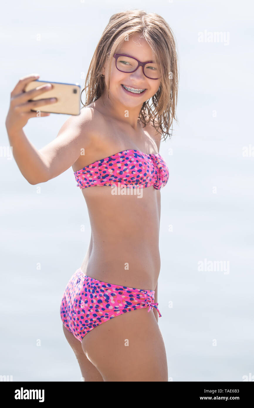 Glückliche junge Mädchen mit Zahnspangen, selfhie am Strand im Sommer heissen Tag. Stockfoto