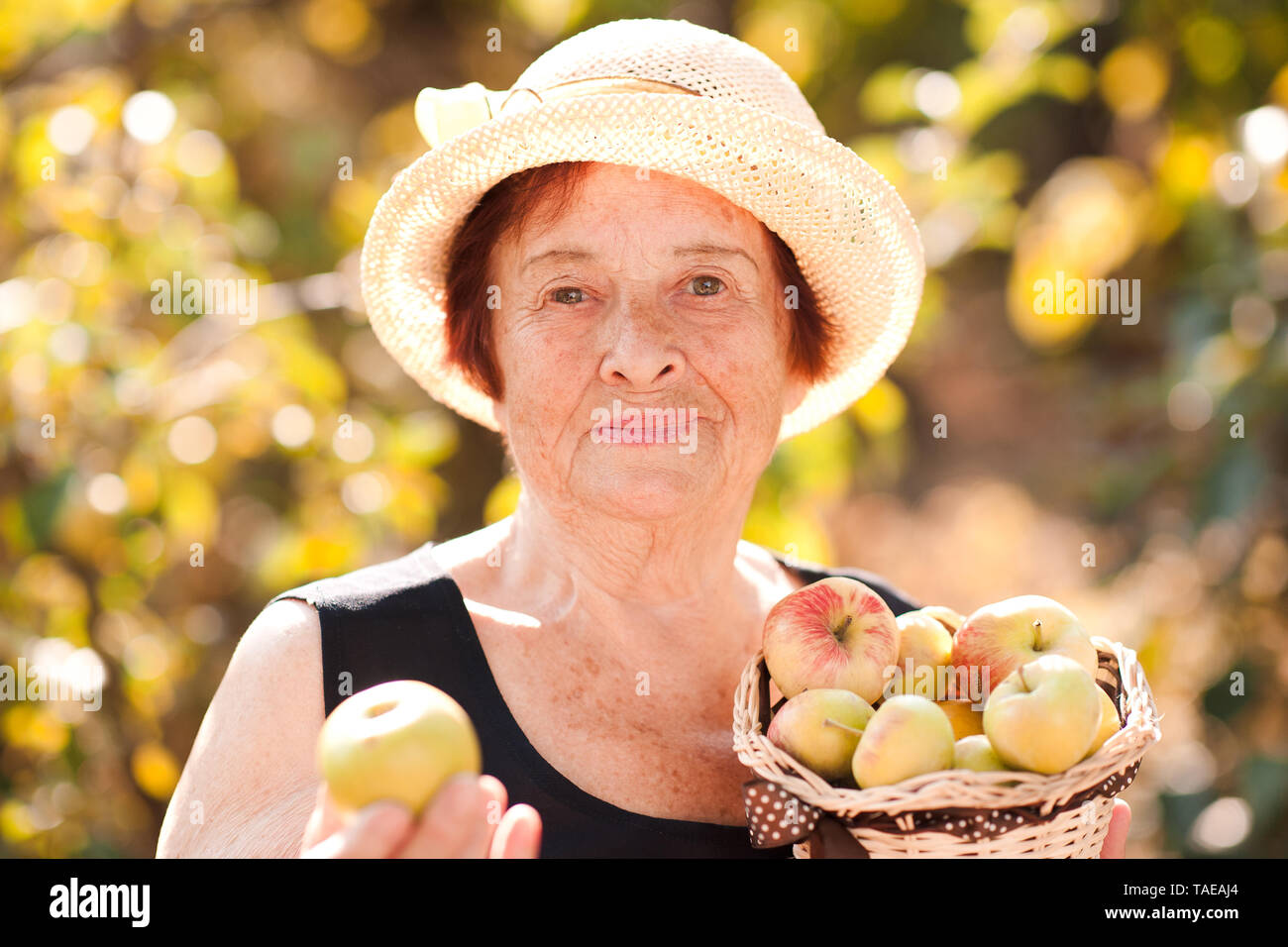 Gerne ältere Frau mit Äpfel im Freien. Mit Blick auf die Kamera. Stockfoto