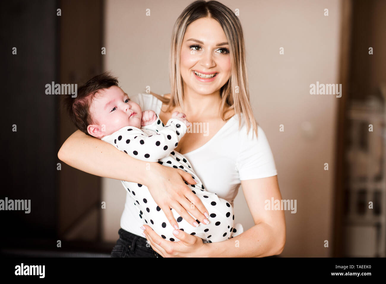 Happy Mother Holding Baby auf Hände im Zimmer. Die Mutterschaft. Mutterschaft. Stockfoto