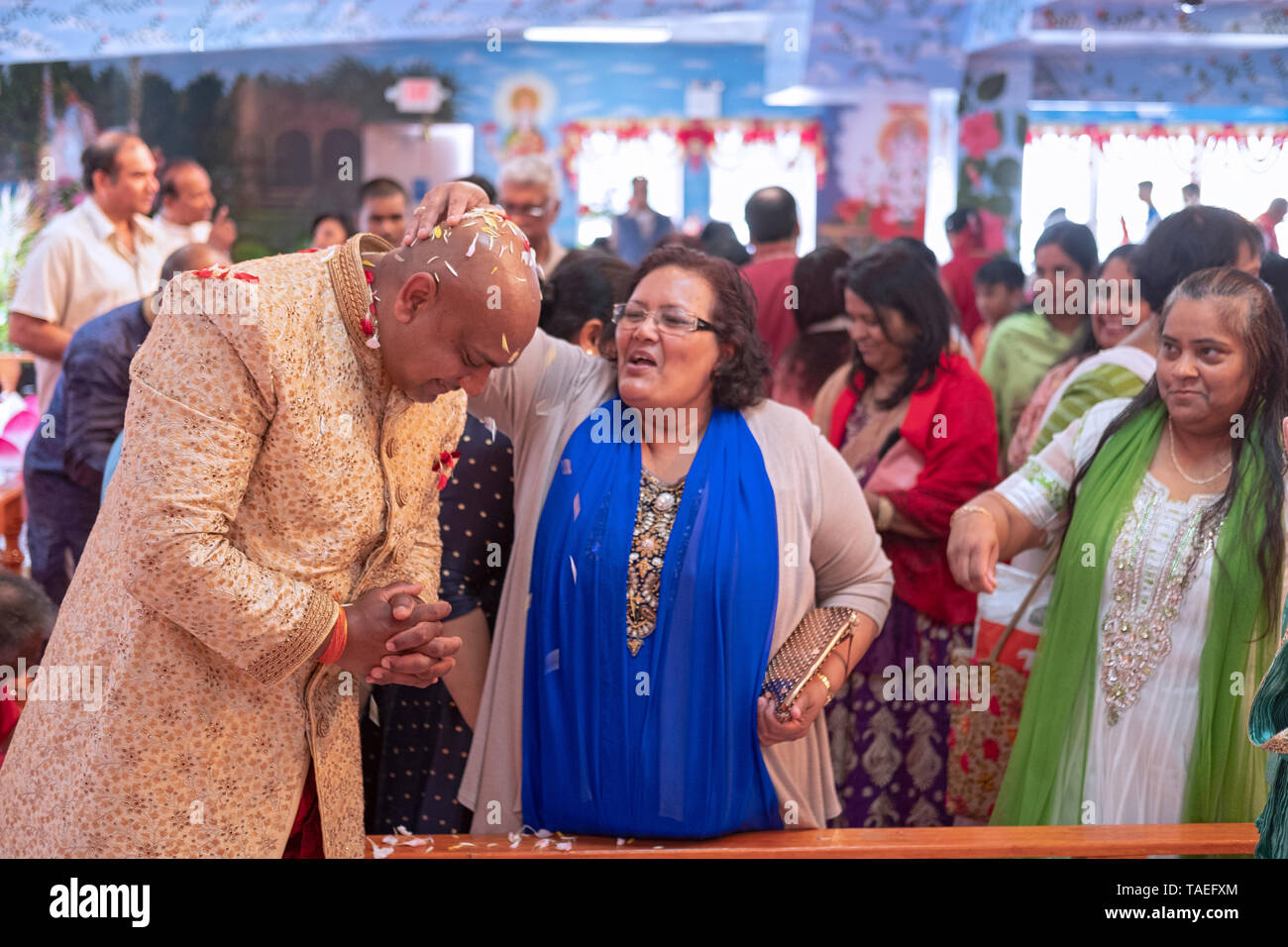 Anbeter streuen Blütenblätter auf einem hinduistischen Mann in den fünfziger Jahren, die in der Morgen Dienstleistungen in seinem Tempel unterstützt seinen Geburtstag zu feiern. In Queens. Stockfoto