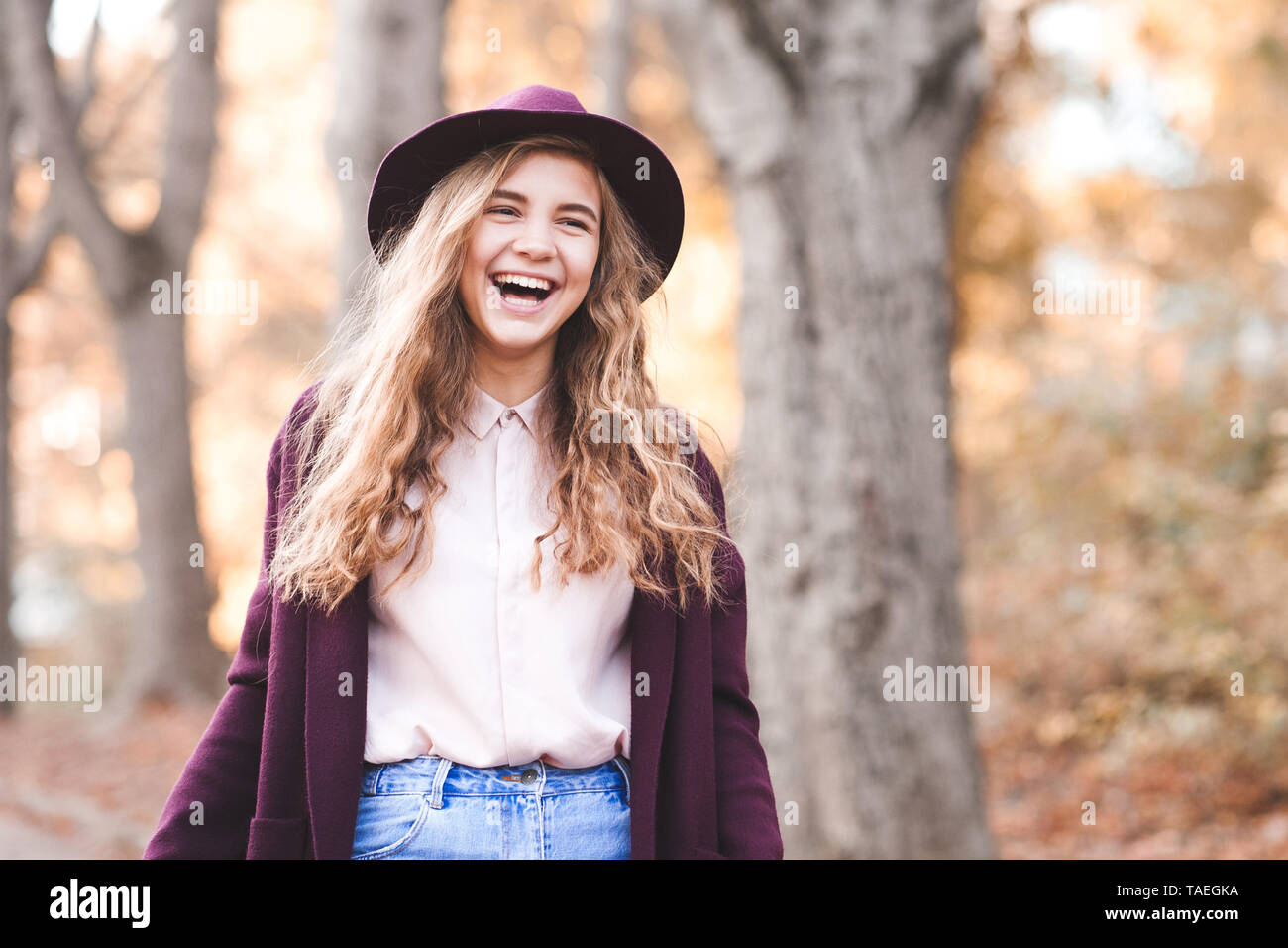 Lachend jugendlich Mädchen 14-16 Jahre alten trug Hut und Jacke walking im Park. Mit Blick auf die Kamera. Teenagerhood. Stockfoto