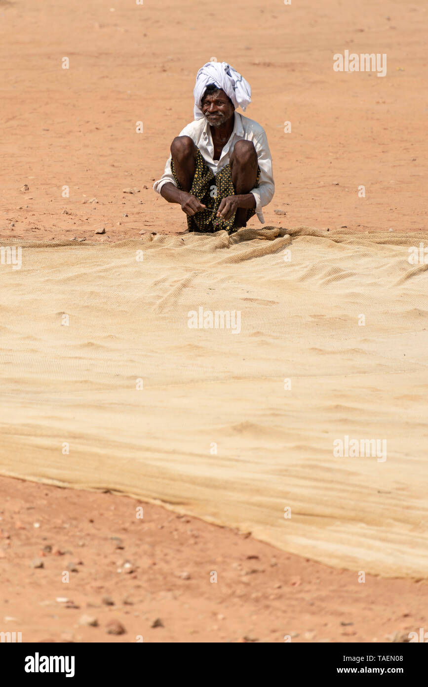 Vertikale Portrait von ein alter Fischer Flicken der Netze in Indien. Stockfoto