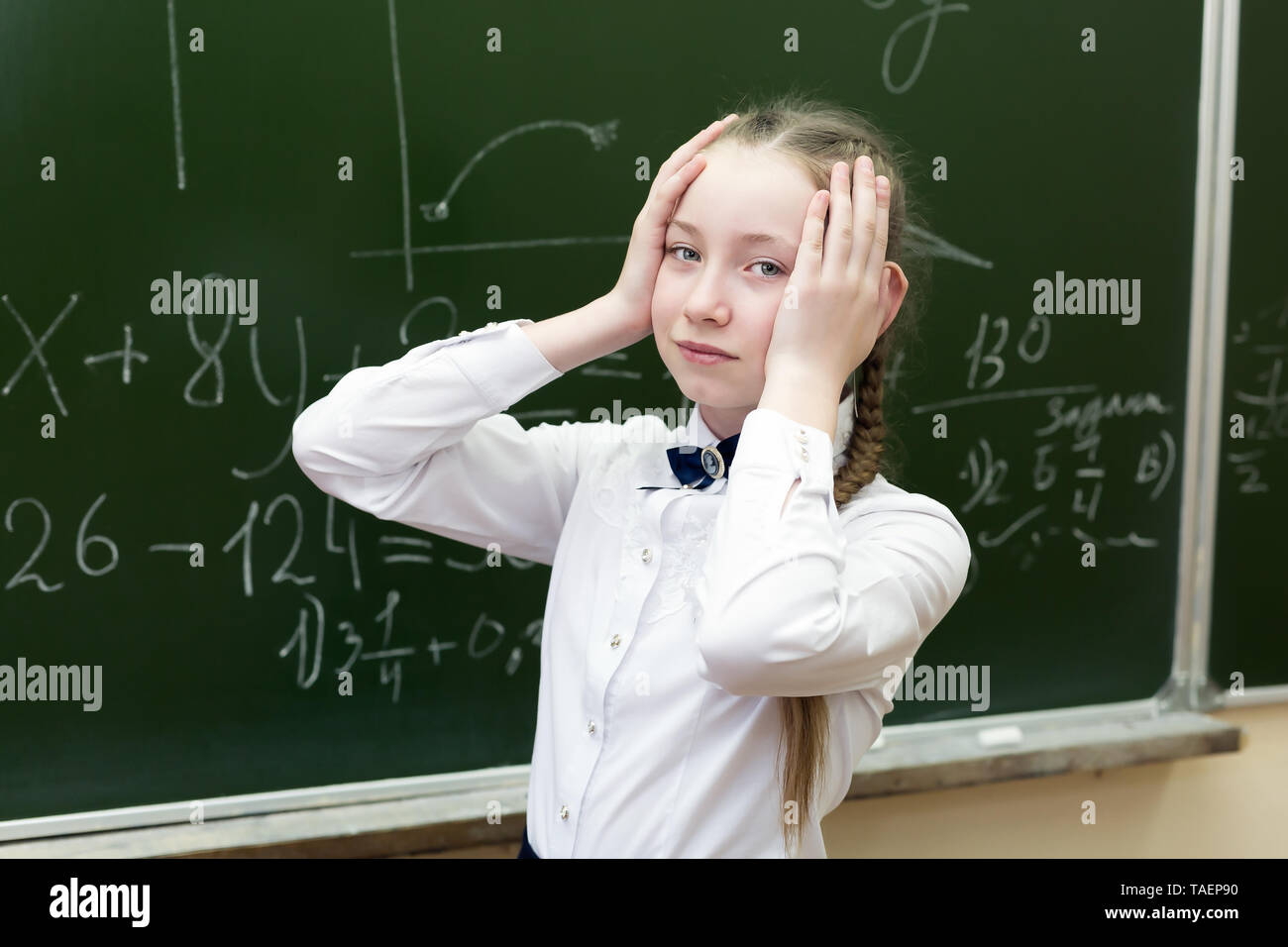 Mädchen Schüler ihre Hände über ihren Kopf halten Spannung Müdigkeit, die Lösung einer schwierigen Aufgabe in Mathematik. Stockfoto