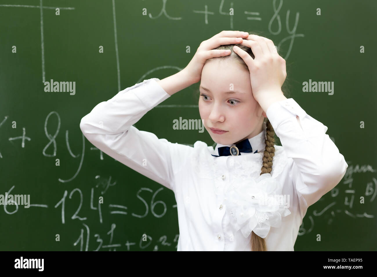 Mädchen Schüler ihre Hände über ihren Kopf halten Spannung Müdigkeit, die Lösung einer schwierigen Aufgabe in Mathematik. Stockfoto