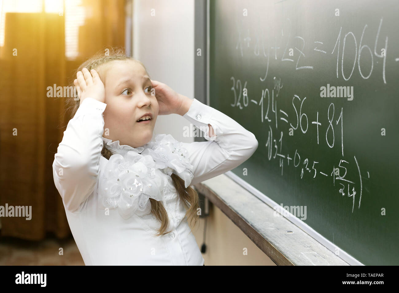 Mädchen Schüler ihre Hände über ihren Kopf halten Spannung Müdigkeit, die Lösung einer schwierigen Aufgabe in Mathematik. Stockfoto