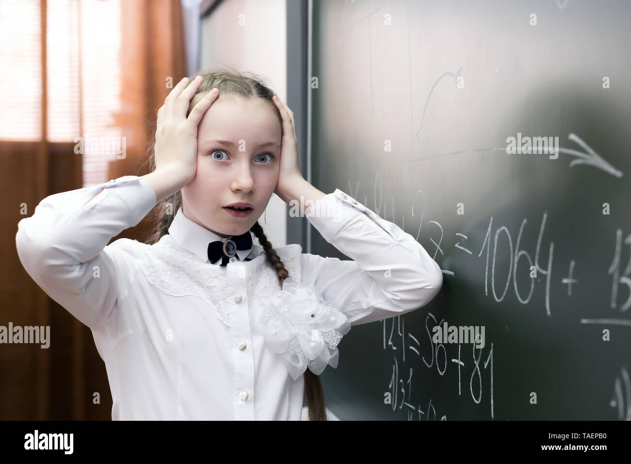 Mädchen Schüler ihre Hände über ihren Kopf halten Spannung Müdigkeit, die Lösung einer schwierigen Aufgabe in Mathematik. Stockfoto