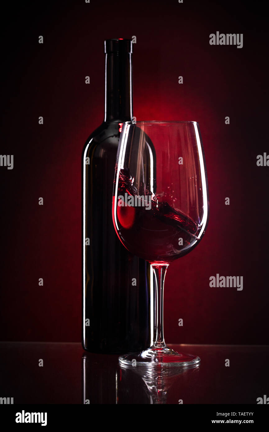 Wein Glas und Flasche Rotwein auf einem dunklen Hintergrund rot Stockfoto