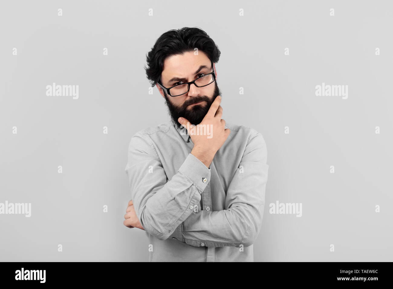 Nachdenklich ernsten Mann mit Brille, bärtigen denken Kerl über grauer Hintergrund Stockfoto