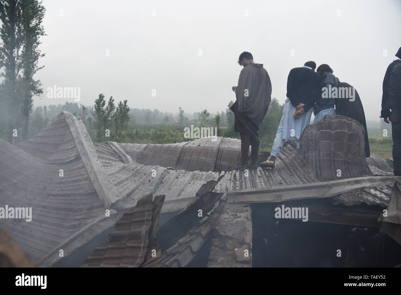 Kaschmir Männer gesehen, dass ein Krieg verwüsteten Haus nach einem gunbattle in Pulwama, südlich von Srinagar. Zakir Ahmed Rashid Bhat Alias Musa war spät am Donnerstag durch die Sicherheitskräfte in Pulwama Bezirk getötet, als Sicherheitskräfte ein Cordon und Suchen in Dadsara Dorf zentralen Bereich gestartet hatte, südlich von Srinagar nach Informationen über militante Präsenz. Stockfoto