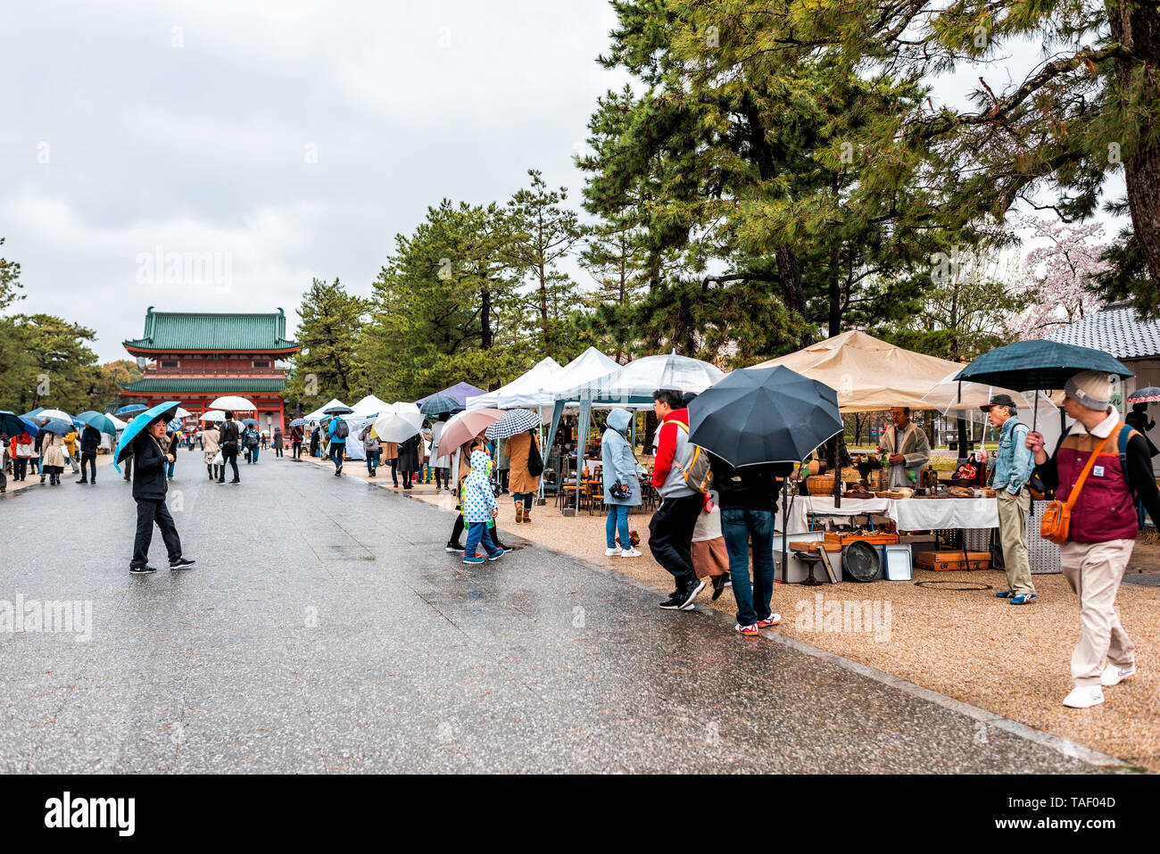 Kyoto, Japan - 10 April, 2019: Menschen mit Sonnenschirmen während der regnerischen Tag Wandern in Wet Market in Okazaki Park mit Blick auf den Heian-schrein Stockfoto