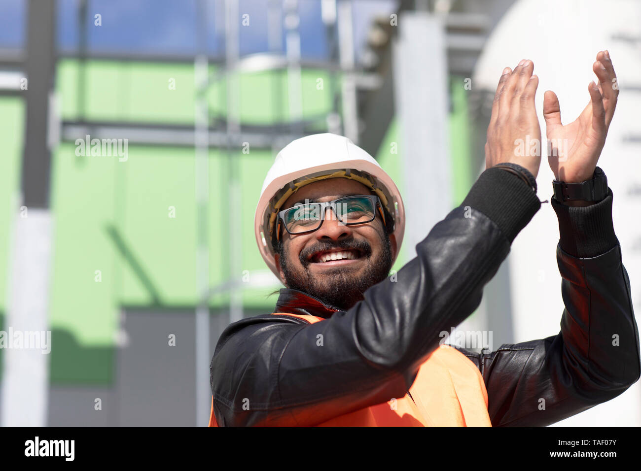 Portrait von glücklichen Konstrukteur vor Power Station das Tragen von Helm und Warnweste Händeklatschen Stockfoto