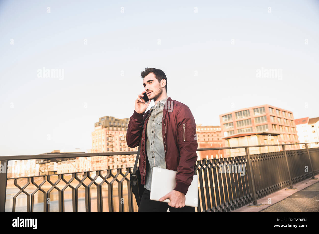Junger Mann mit Tablet Gespräch am Handy auf einer Brücke in der Stadt Stockfoto