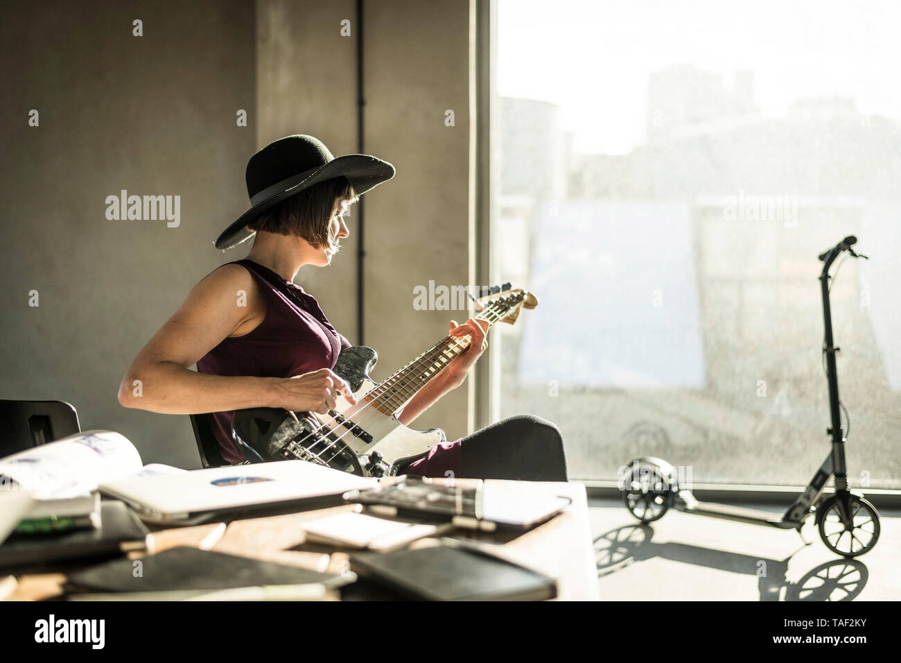 Frau mit Hut im Büro, spielt er Gitarre Stockfoto