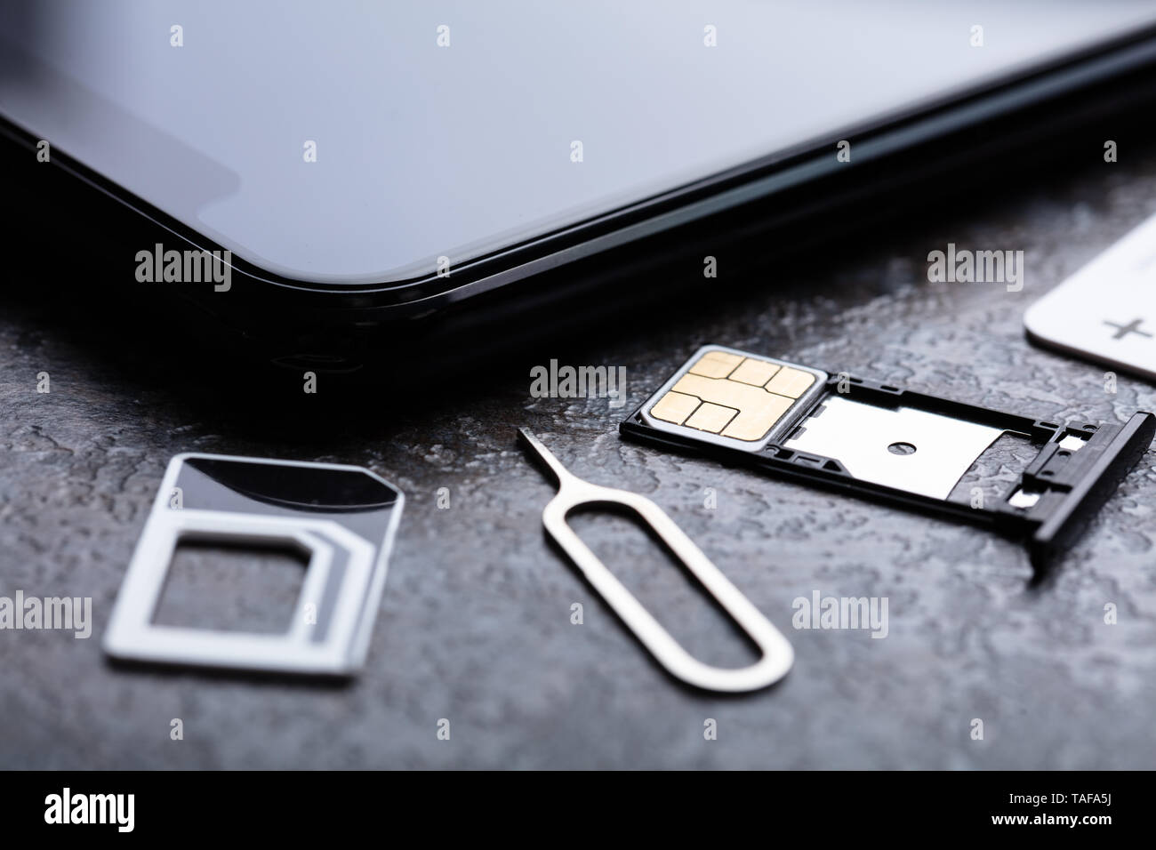 Handy in der Nähe von Nano-SIM-Karte in den Card Adapter mit Eject Pin über konkreten Hintergrund Stockfoto