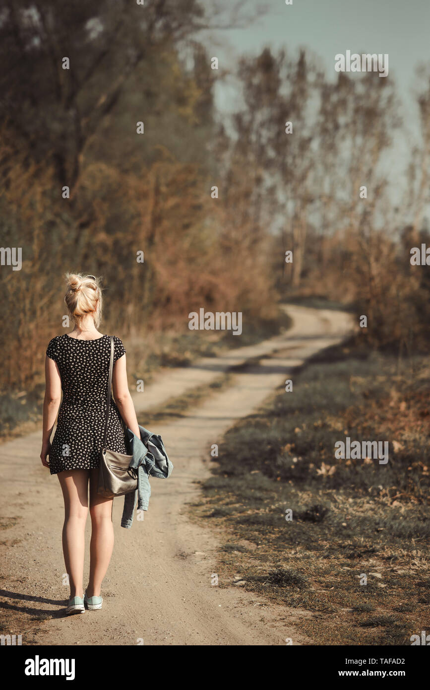 Junge Frau zu Fuß auf unbefestigte Straße Stockfoto