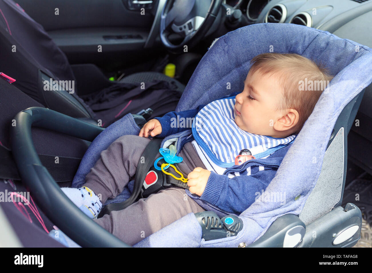 Süßes kleines Kind schlafen im Auto mit Sicherheitsgurt für Sicherheit  während der Reise befestigt Stockfotografie - Alamy