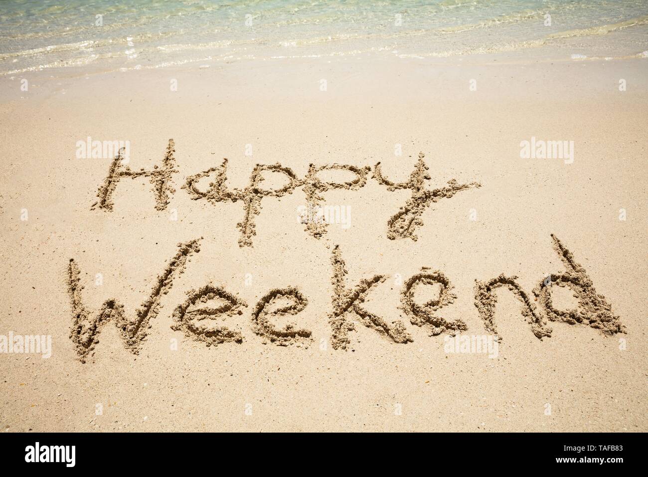 Happy Weekend Text in Sand in der Nähe des idyllischen Meer am Strand Stockfoto