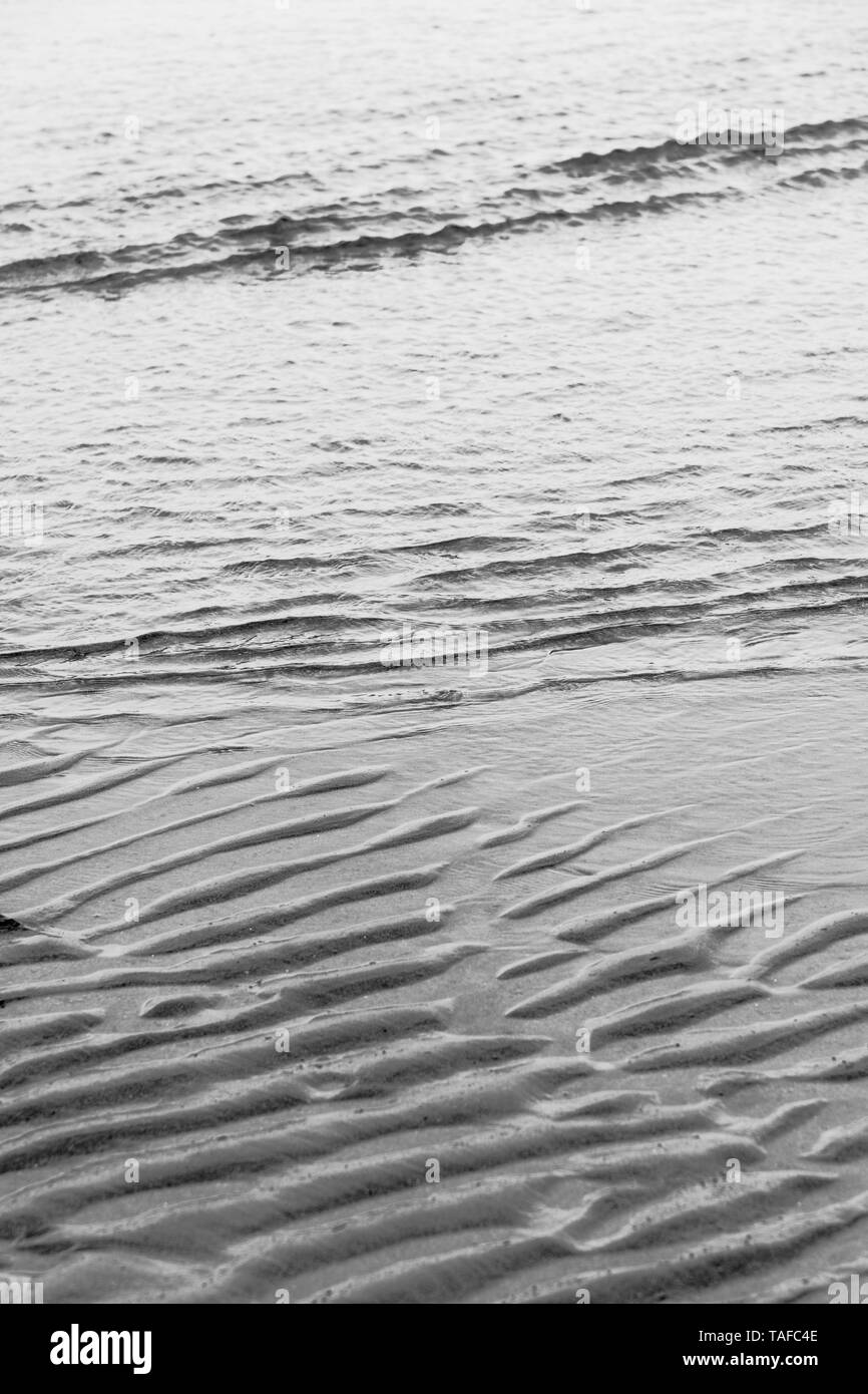3monochromatischen Bilder von ebbing Tide - gewinkelt Klein wavelets - und Wasser plätscherte Sand markiert. Metapher "Tide und Zeit', klicken Sie mit der Strömung. Stockfoto