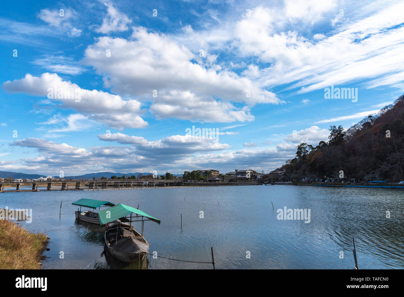 Boot an Hozu-gawa Fluss und Togetsu-kyo Brücke mit bunten Wald Berg Hintergrund in Arashiyama, Kyoto, Japan. Arashiyama ist ein National Desig Stockfoto