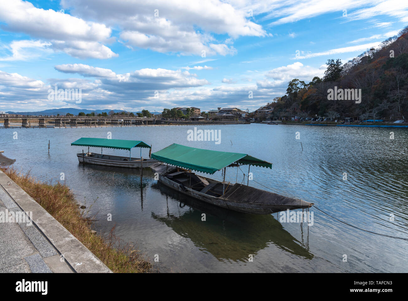Boot an Hozu-gawa Fluss und Togetsu-kyo Brücke mit bunten Wald Berg Hintergrund in Arashiyama, Kyoto, Japan. Arashiyama ist ein National Desig Stockfoto