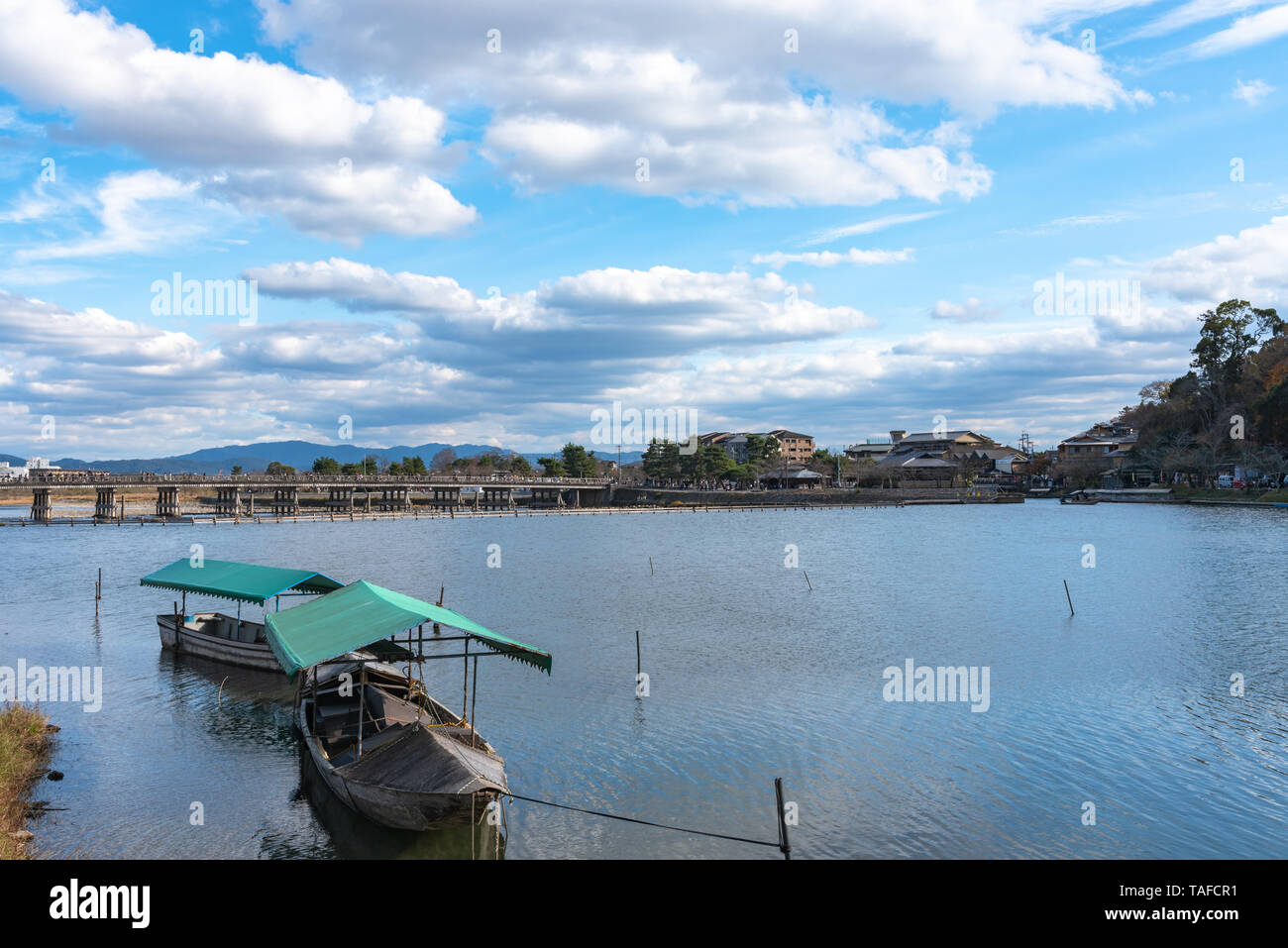 Boot an Hozu-gawa Fluss und Togetsu-kyo Brücke mit bunten Wald Berg Hintergrund in Arashiyama, Kyoto, Japan. Arashiyama ist ein National Desig Stockfoto