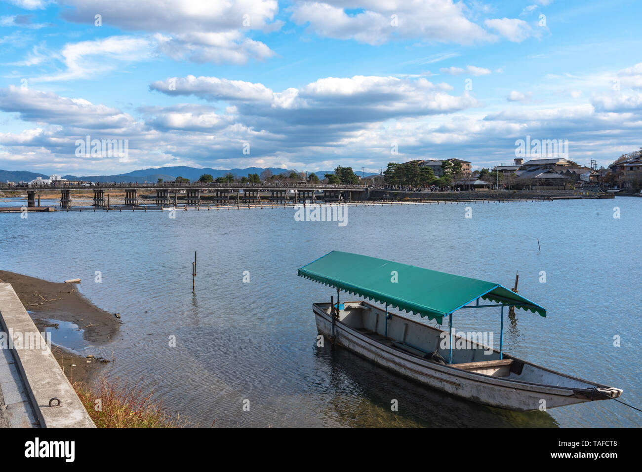 Boot an Hozu-gawa Fluss und Togetsu-kyo Brücke mit bunten Wald Berg Hintergrund in Arashiyama, Kyoto, Japan. Arashiyama ist ein National Desig Stockfoto