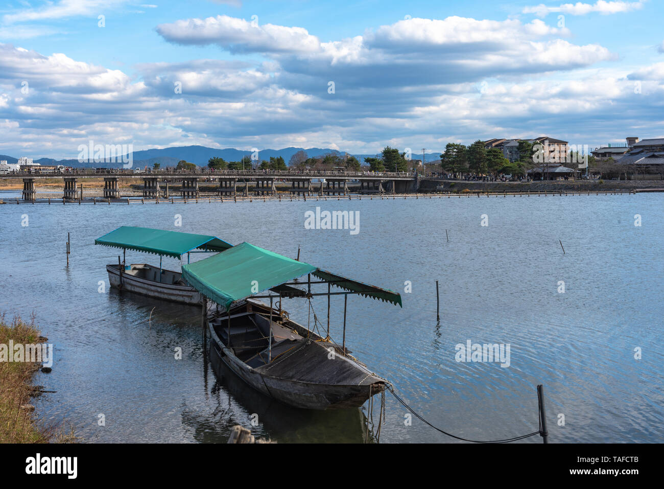 Boot an Hozu-gawa Fluss und Togetsu-kyo Brücke mit bunten Wald Berg Hintergrund in Arashiyama, Kyoto, Japan. Arashiyama ist ein National Desig Stockfoto