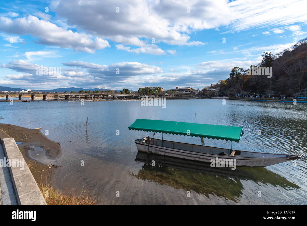 Boot an Hozu-gawa Fluss und Togetsu-kyo Brücke mit bunten Wald Berg Hintergrund in Arashiyama, Kyoto, Japan. Arashiyama ist ein National Desig Stockfoto