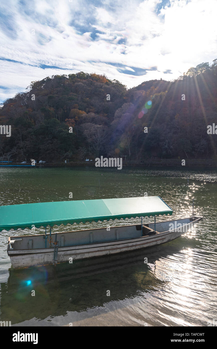 Boot an Hozu-gawa Fluss und Togetsu-kyo Brücke mit bunten Wald Berg Hintergrund in Arashiyama, Kyoto, Japan. Arashiyama ist ein National Desig Stockfoto