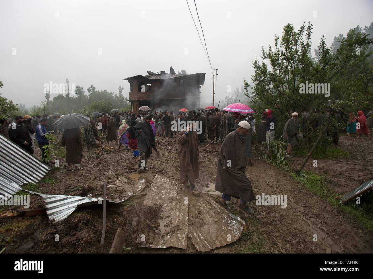 Srinagar, Indisch kontrollierten Teil Kaschmirs. 24. Mai, 2019. Menschen versammeln sich in der Nähe ein Haus in eine Schießerei beschädigt im Village Dadsara der Zentralen in Pulwama Bezirk, etwa 39 km südlich von Srinagar Stadt, die Hauptstadt des Indischen-kontrollierten Kaschmir, 24. Mai 2019. Eine militante Commander und Leiter der al-Qaida affiliate Ansar Gazwatul Hind - Zakir Musa war Donnerstag Abend in eine Schießerei mit den Streitkräften der Regierung in unruhigen Indischen getötet - Kaschmir gesteuert, sagte die Polizei. Credit: Javed Dar/Xinhua/Alamy leben Nachrichten Stockfoto