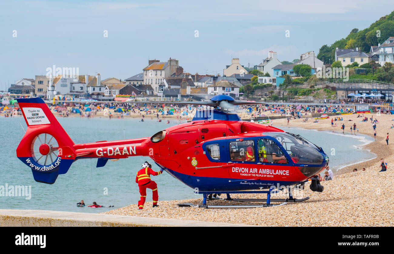 Lyme Regis, Dorset, Großbritannien. 25. Mai 2019. Devon Air Ambulance Hubschrauber landet auf der überfüllten Strand in Lyme Regis. Der Hubschrauber bereitet sich auf von der überfüllten Strand mit einem Patienten an Bord. Credit: Celia McMahon/Alamy Leben Nachrichten. Stockfoto