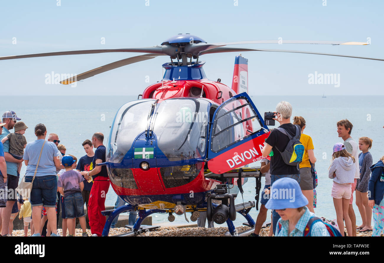 Lyme Regis, Dorset, Großbritannien. 25. Mai 2019. UK Wetter: Massen von Touristen und Besucher in Scharen zu den Strand in Lyme Regis in der heißen Sonne aalen. Die Devon Air Ambulance helicopter erzeugt das Interesse der Zuschauer, wie es zu einem Notfall auf dem belebten Strand besucht. Credit: Celia McMahon/Alamy Leben Nachrichten. Credit: Celia McMahon/Alamy leben Nachrichten Stockfoto