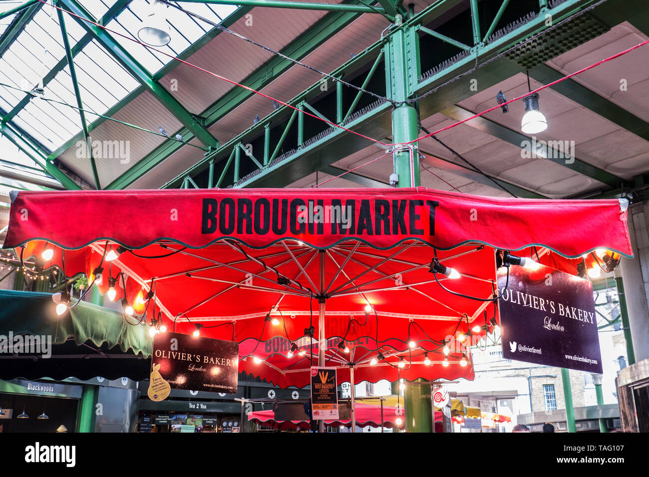 Borough Market'oliviers Bäckerei' Standbesitzer eingebrannten roten Sonnenschirm mit beleuchteten Display Glühbirnen innerhalb der traditionellen Southwark Markt Southwark London UK Stockfoto
