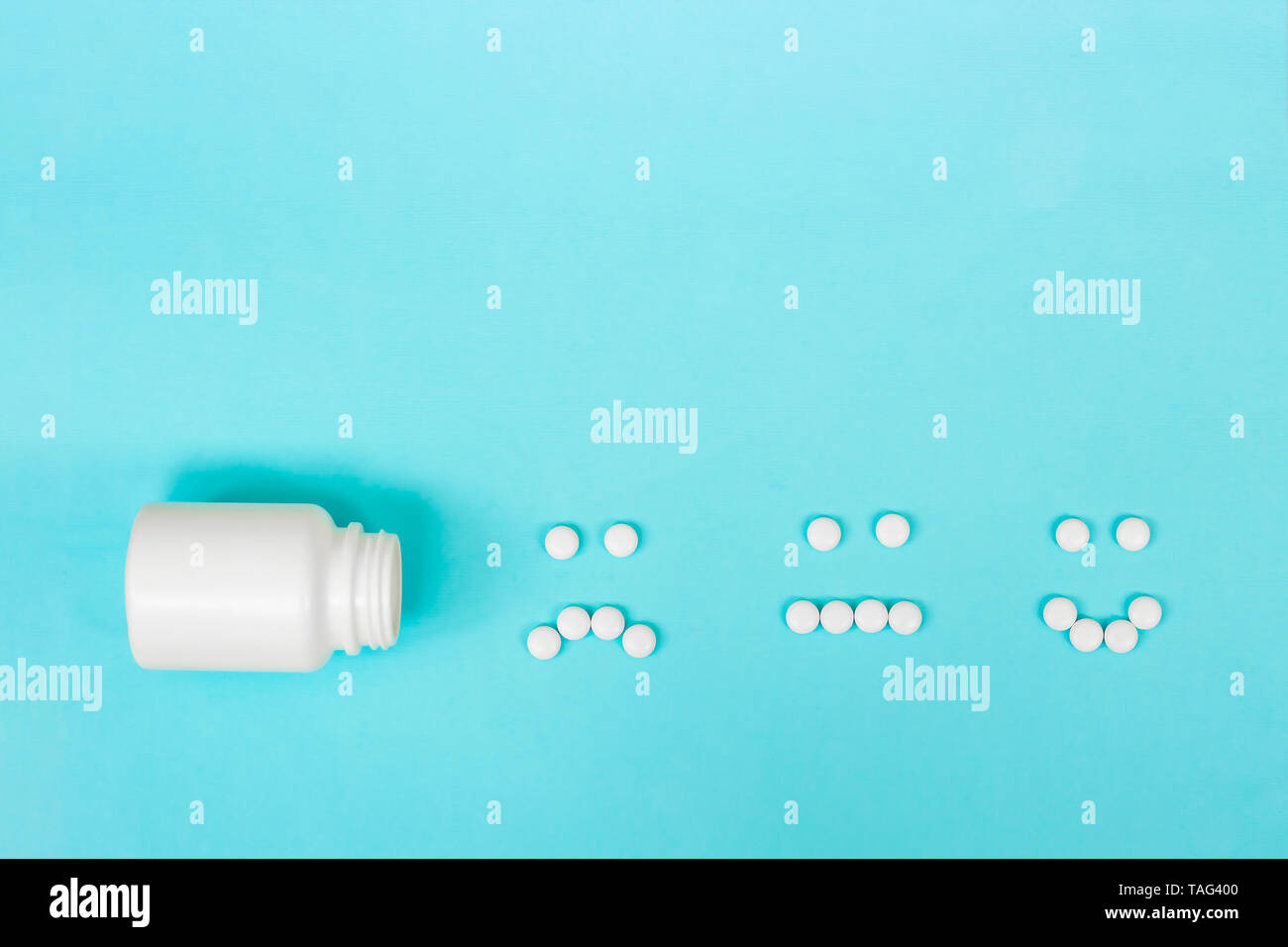Lustige Gesichter aus Pillen und eine Plastikflasche auf blauem Hintergrund. Das Konzept von Antidepressiva und Heilung. Kopieren Sie Platz. Ansicht von oben. Stockfoto