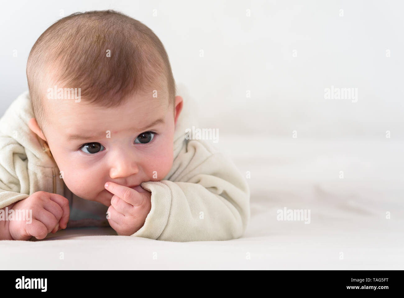 Portrait einer bezaubernd lächelnde Baby beißen Ihre eigenen Finger