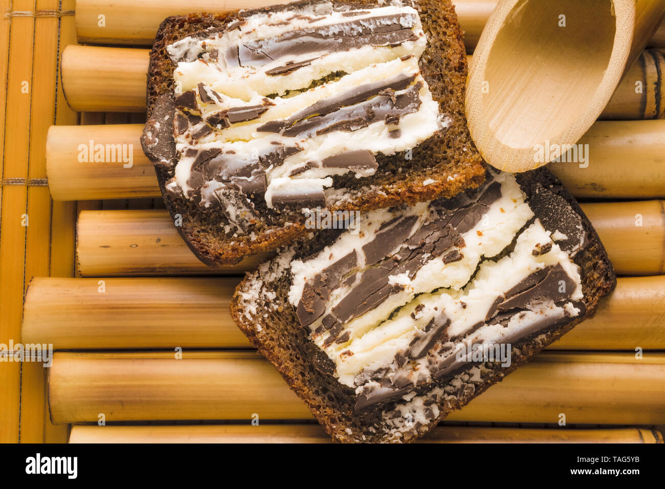 Sandwich mit grober, schwarzer Korn Brot und süßen Quark und dunkler Schokolade auf einem Bambus stehen und Bambus Serviette. Lecker einfach gesundes Frühstück in Th Stockfoto