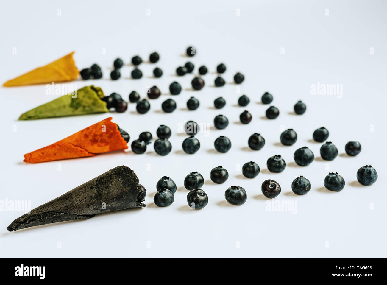 Vier Eis Waffeln in verschiedenen Farben gefüllt mit Blaubeeren auf weißem Hintergrund mit Kopie Raum isoliert. Stockfoto