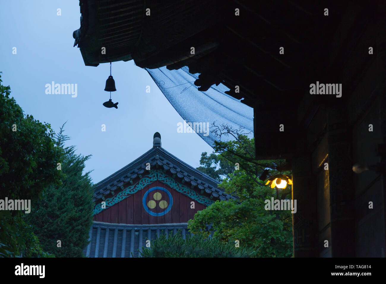 Ein Fisch geformt Wind chime unter dem Tempel Dach Silhouetten gegen die dusking Himmel am Bongeunsa Tempel hängen. Seoul, Südkorea. Stockfoto