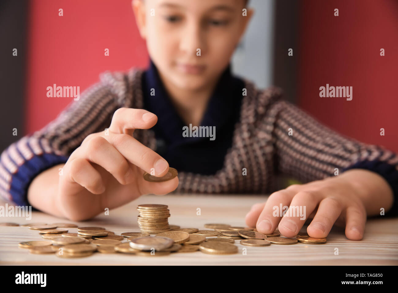 Süße kleine Jungen mit Münzen bei Tisch sitzen. Konzept der Child Support Stockfoto