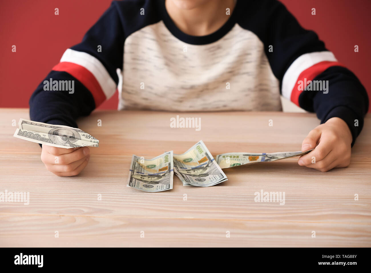 Süße kleine Jungen mit Dollar Banknoten an den hölzernen Tisch. Konzept der Child Support Stockfoto