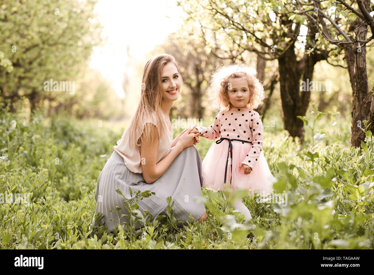 Lächelnde Frau mit baby girl in der Wiese im Freien posieren. Mit Blick auf die Kamera. Die Mutterschaft. Mutterschaft. Stockfoto