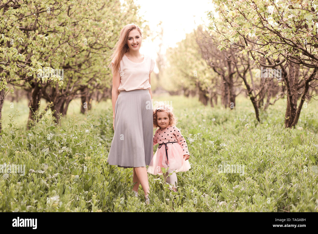 Glückliche Mutter mit Baby Tochter im Garten posieren. Mit Blick auf die Kamera. Die Mutterschaft. Stockfoto