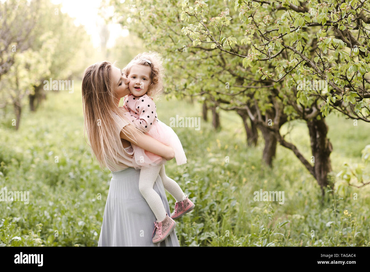 Mutter küssen Baby Mädchen 2-3 Jahre alten Park über grüne Natur Hintergrund. Die Mutterschaft. Mutterschaft. Stockfoto