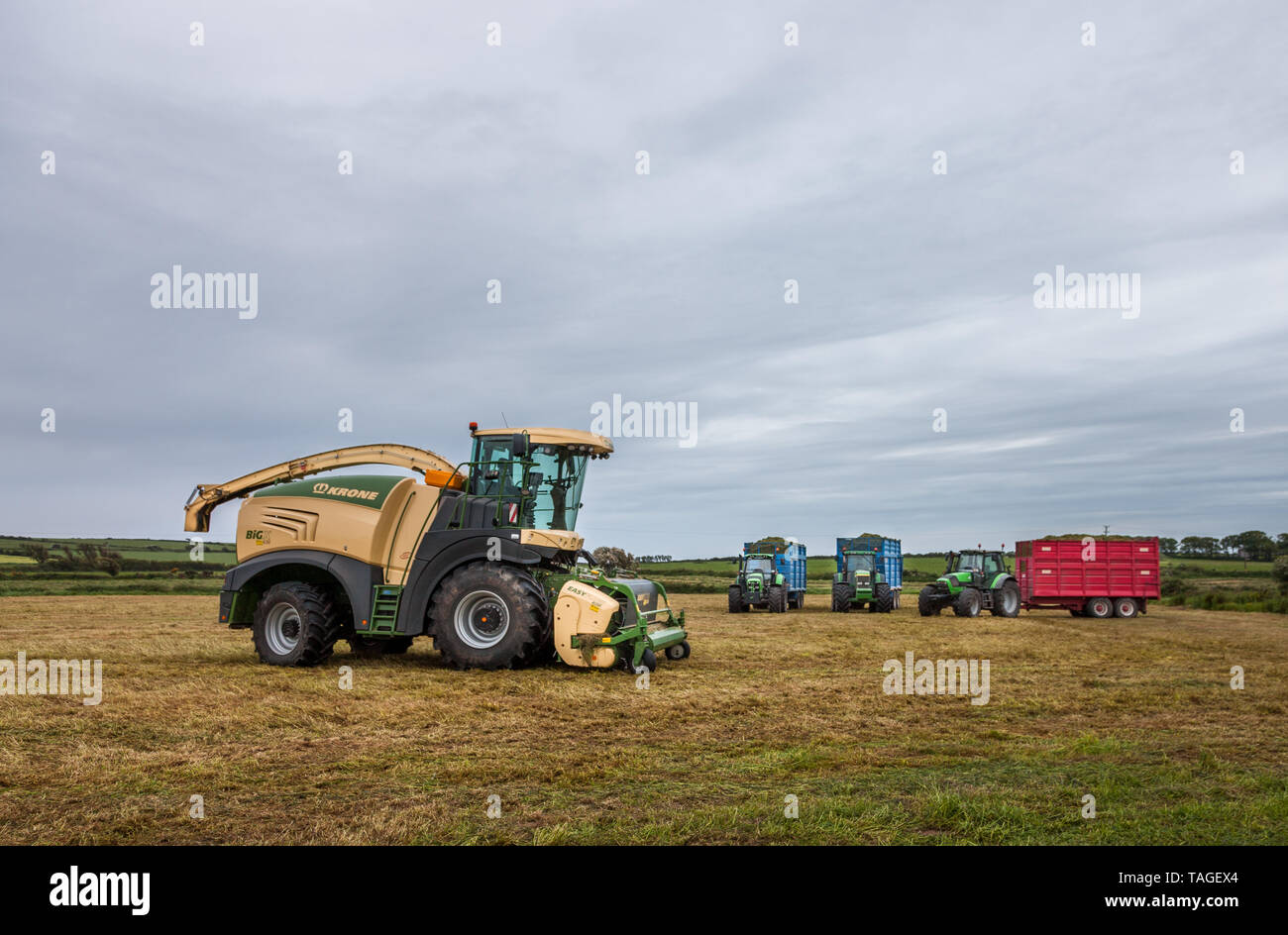 Garryvoe, Cork, Irland. 25 Mai, 2019. An einem grauen bewölkten Morgen ein Mähdrescher mit Traktoren und Anhängern über Nacht in einem Feld geparkt werden, af Stockfoto