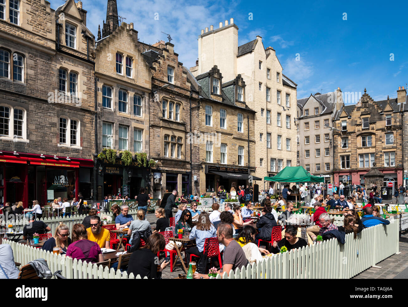 Viele Menschen trinken in Bars im Freien bei schönem Wetter am Grassmarket in der Altstadt von Edinburgh, Schottland, Großbritannien Stockfoto